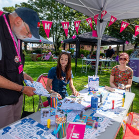 Man speaks with two women at community event stall