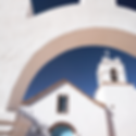 SAN PEDRO DO ATACAMA: Detalhe da arquitetura de adobe branca da Igreja de San Pedro de Atacama, destacando o arco de entrada e a torre do sino contra o céu azul.