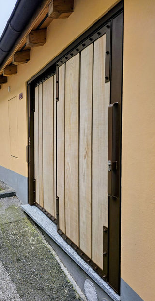 Porta scorrevole in acciaio/ferro termolaccato con tamponatura in assi di castagno. Design moderno e funzionale per ingressi.