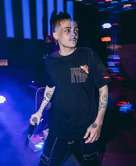 Thank You, Morello performing on stage, holding a microphone, with colorful stage lights in the background. He is an alternative singer/rapper and member of Fallen7.