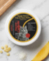 Top view of paw balm with ingredients and mango on the side