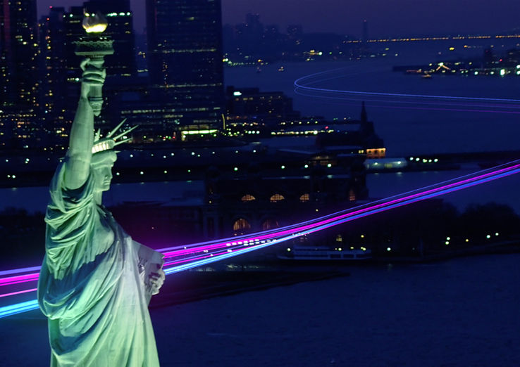 Illuminated light streaks behind the statue of liberty in New York. 
