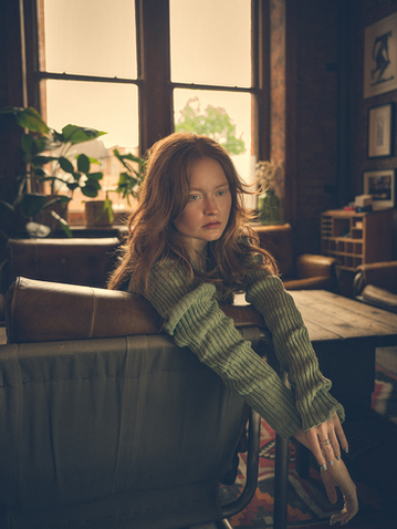 Redhead woman sits pensively in loft