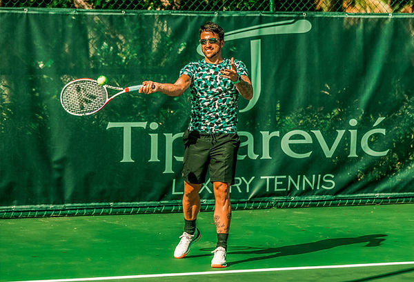 Janko Tipsarevic hitting ball in fronot of his logo.jpg