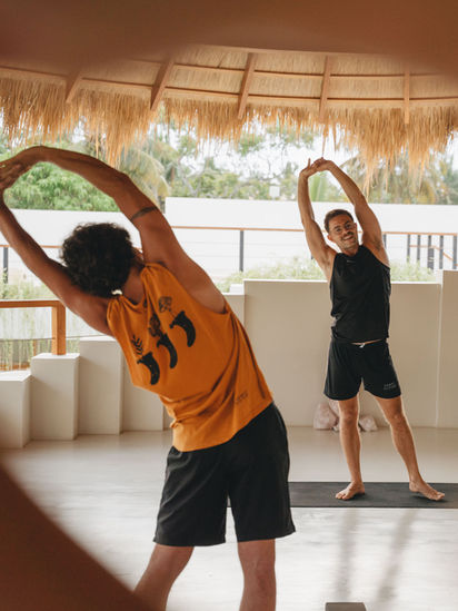 two guy standing at a mobility class doing their training while holding up their arms