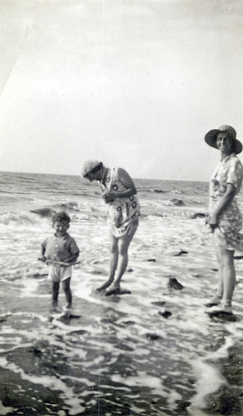 Vintage family smiling and playing at the beach splashing in water