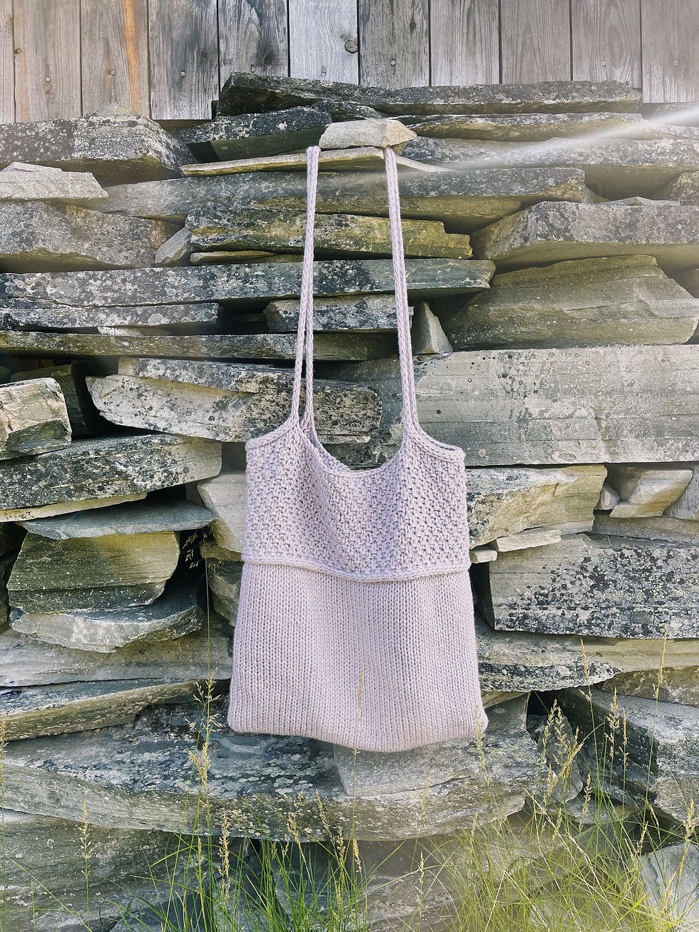 Miniatyrbilde: Hjemmestrikket lilla totebag mot steinvegg