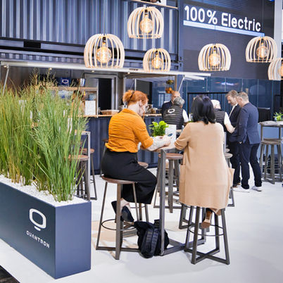 Blick von außen in den Messestand. Frauen sitzen Tischen und sind im Gespräch
