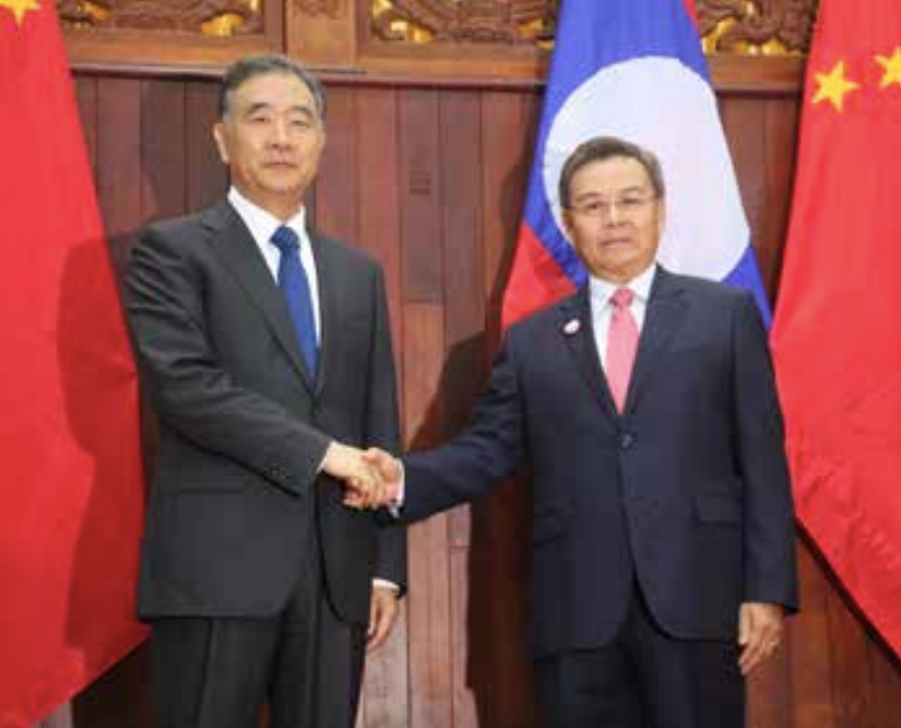 Dr Xaysomphone Phomvihane (right) shakes hands with Mr Wang Yang in Vientiane on Monday.
