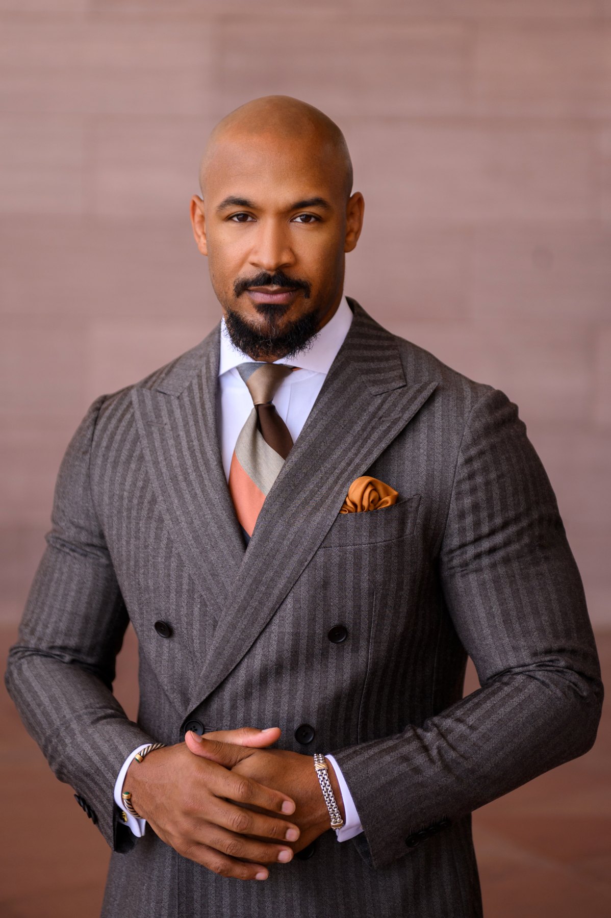 Man in a double-breasted gray pinstripe suit with a striped tie and gold pocket square