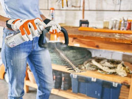 Woman spraying blade of a hedge trimmer