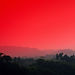 Red sky over rolling hills during sunset, with silhouettes of trees Great Kerala.