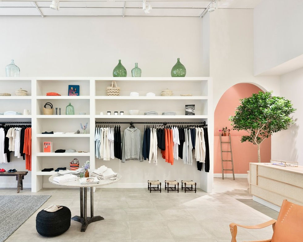 a store with clothes hanging on racks and a table with a book that says ' vogue ' on it