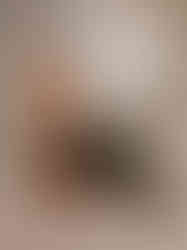 a woman in a brown sweater sits on a wooden stool