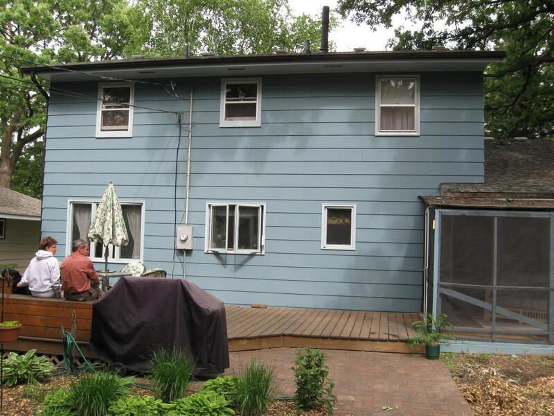 Back of house prior to Sunroom addition. Plain two-story with light blue siding and white windows.