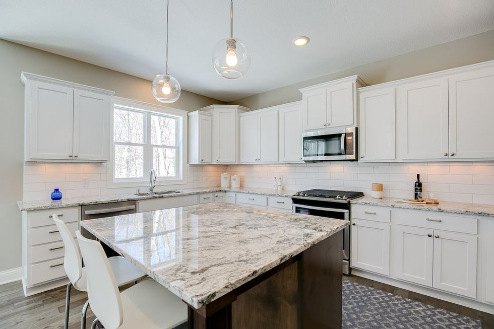 Another image of a light colored kitchen with white cabinets, granite countertops, microwave over range, and window with a view.