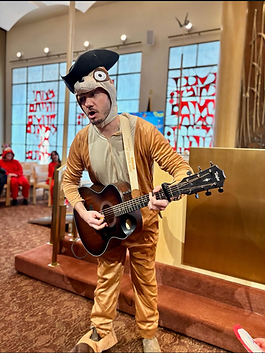 Rabbi Daniel Reichenbach plays guitar in a Purim costume during a synagogue program.