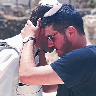 Rabbi Daniel Reichenbach stands closely with another worshipper wearing a tallit at the Western Wall.