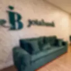 Logotipo da Joiabank na parede sobre sofá verde.