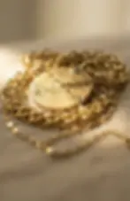 Colar de ouro com medalha texturizada sobre fundo neutro