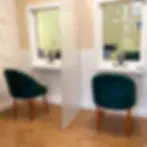 Cabines individuais de atendimento com cadeiras verdes e divisória.