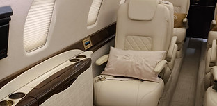 Interior de aeronave executiva com acabamento premium em couro e detalhes sofisticados.