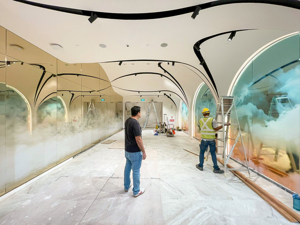 A man works intently on a mural inside a building, bringing color and life to the space with his artistic expression.