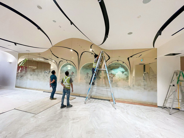 A man works intently on a mural inside a building, bringing color and life to the space with his artistic expression.
