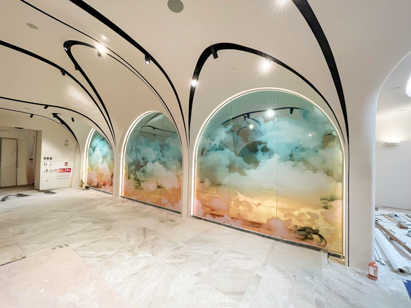 A room featuring a large glass wall adorned with artistic cloud paintings, creating a serene and airy atmosphere.