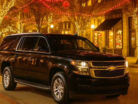 Black Chevrolet Suburban parked on a holiday-lit city street with twinkling lights and decorated storefronts, representing luxury transportation for seasonal events in Austin.