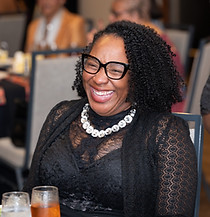 Black woman laughing at formal dinner event