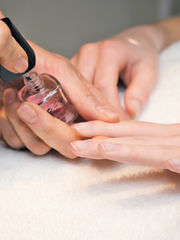 Esthéticienne réalisant une pose de vernis semi-permanent sur les ongles d’une cliente manucure