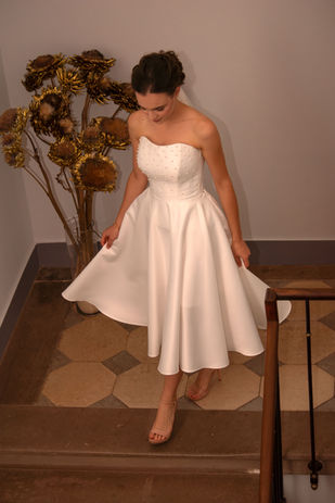 Robe de mariée courte en satin duchesse, longueur midi avec des perles. Robe féminine avec corset