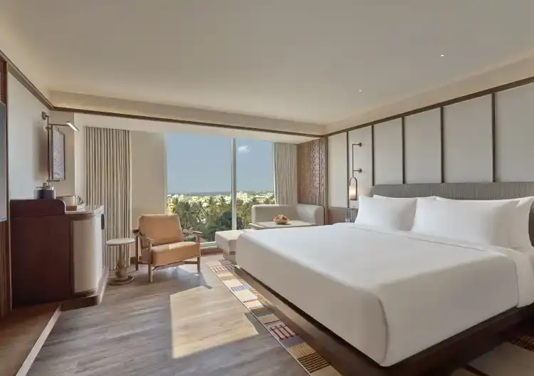The hotel's colour palette traces the life cycle of a coffee bean, from soft whites and light browns deepening into richer chocolate tones, accented with dusty pinks and rust. Natural materials, vernacular pitched roofs, and intricate carved details create intimate, softly lit spaces that evoke the warmth of being welcomed into a home.