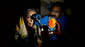 A portable colour fundus imaging device captures retinal image of an island resident in a darkened room