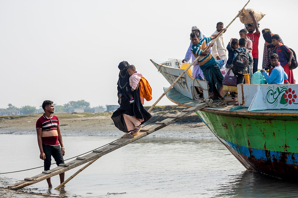 Passengers on a trawler walk down a wooden ramp to disembark from a trawler in the waterside of Char Nizam