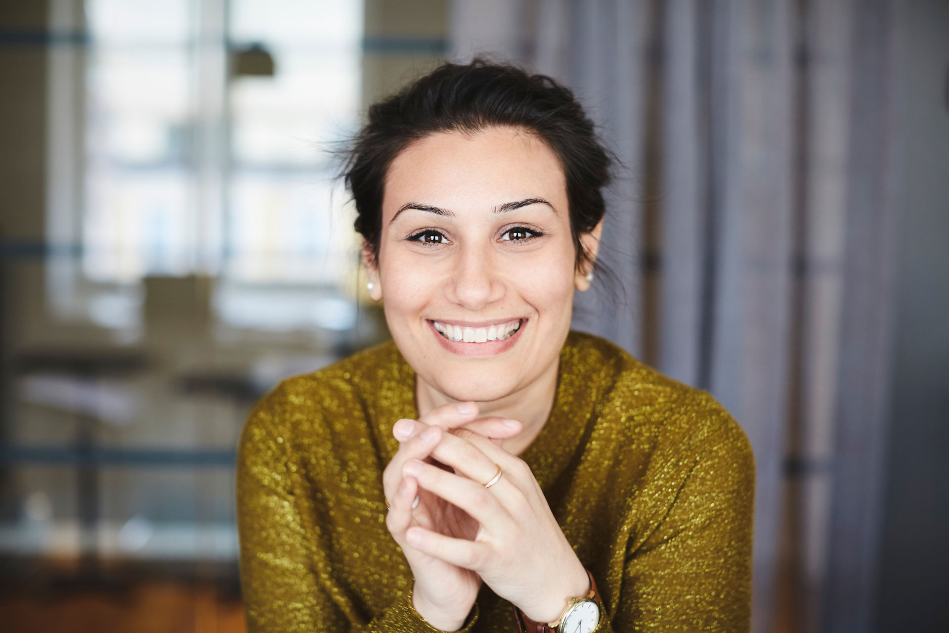 Headshot of an actress wearing gold top while smiling at camera