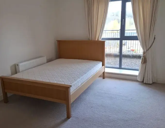 The second bedroom of the Apartment 7 Downview up for sale in Victoria Cross, Cork, shwoing a double bed, large windows, carpeted floor and lots of space.