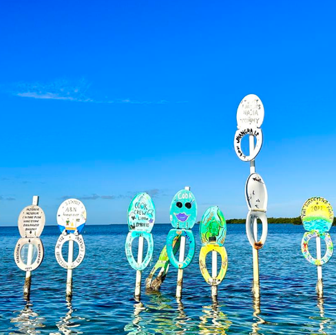 A colorful collection of decorated wooden toilet seats lining the edge of the water at the historic Toilet Seat Cut channel in the Florida Keys