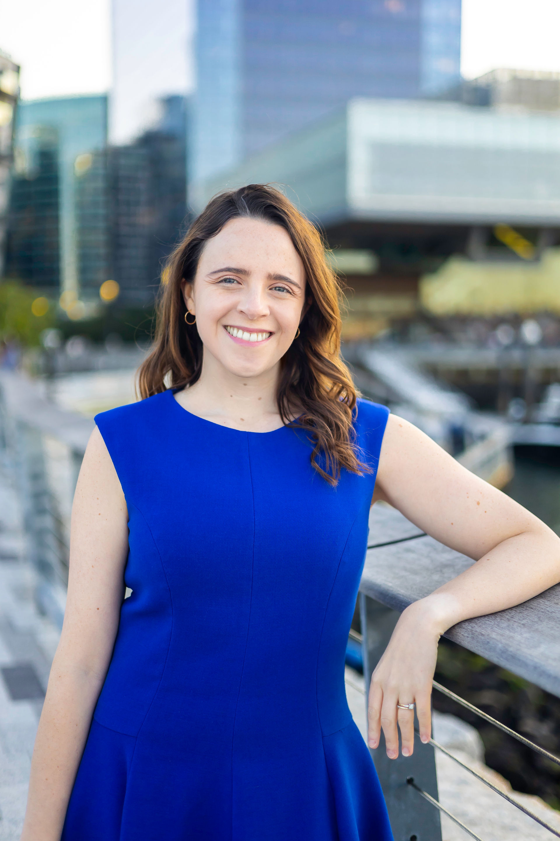 White woman with a blue dress on standing at the pier in the Boston Seaport