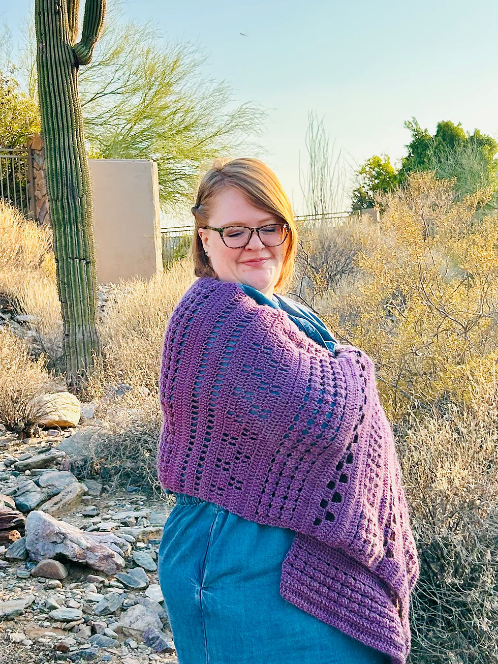Woman in jean dress in the desert wrapped in a purple crochet shawl