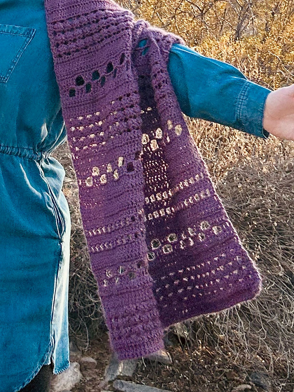 The end of a purple crochet shawl
