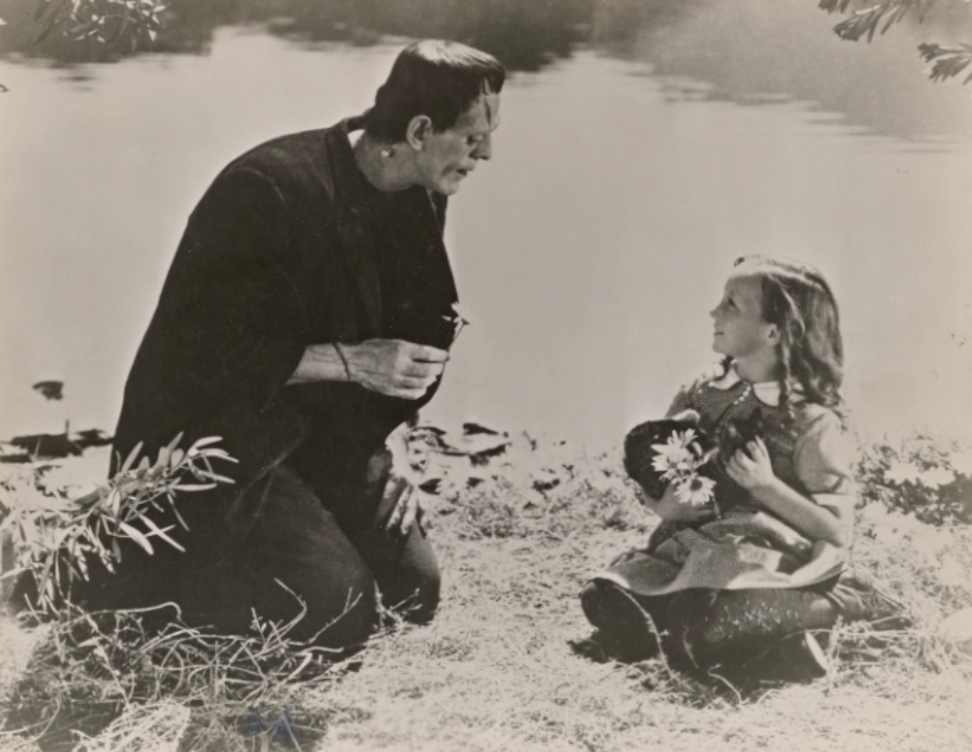 A monster kneels next to a little girl