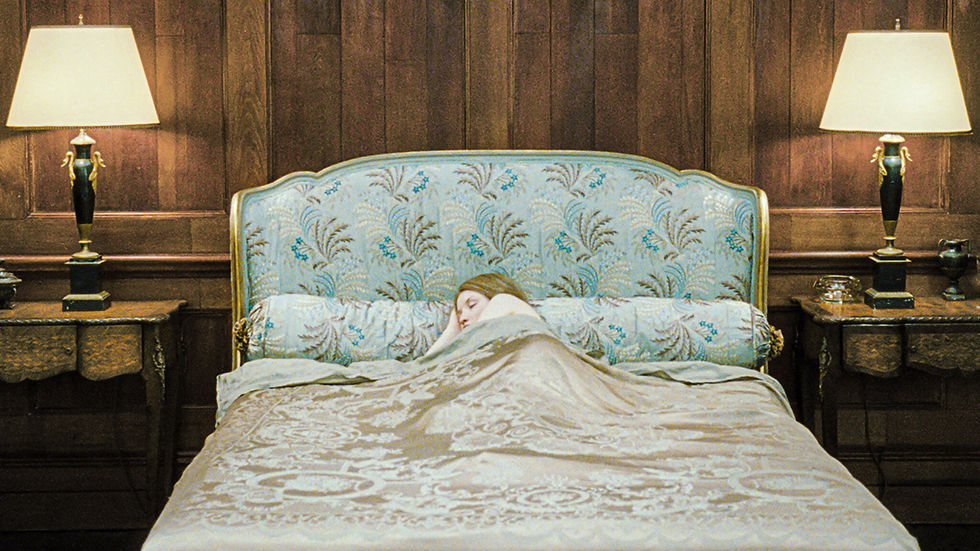A person sleeps in a patterned bed with floral upholstery, flanked by vintage lamps on wooden nightstands, in a cozy, wood-paneled room.