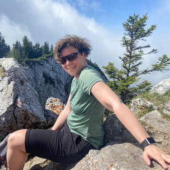 Claudia Fröhlich bei einer Wanderrast auf einem Stein.