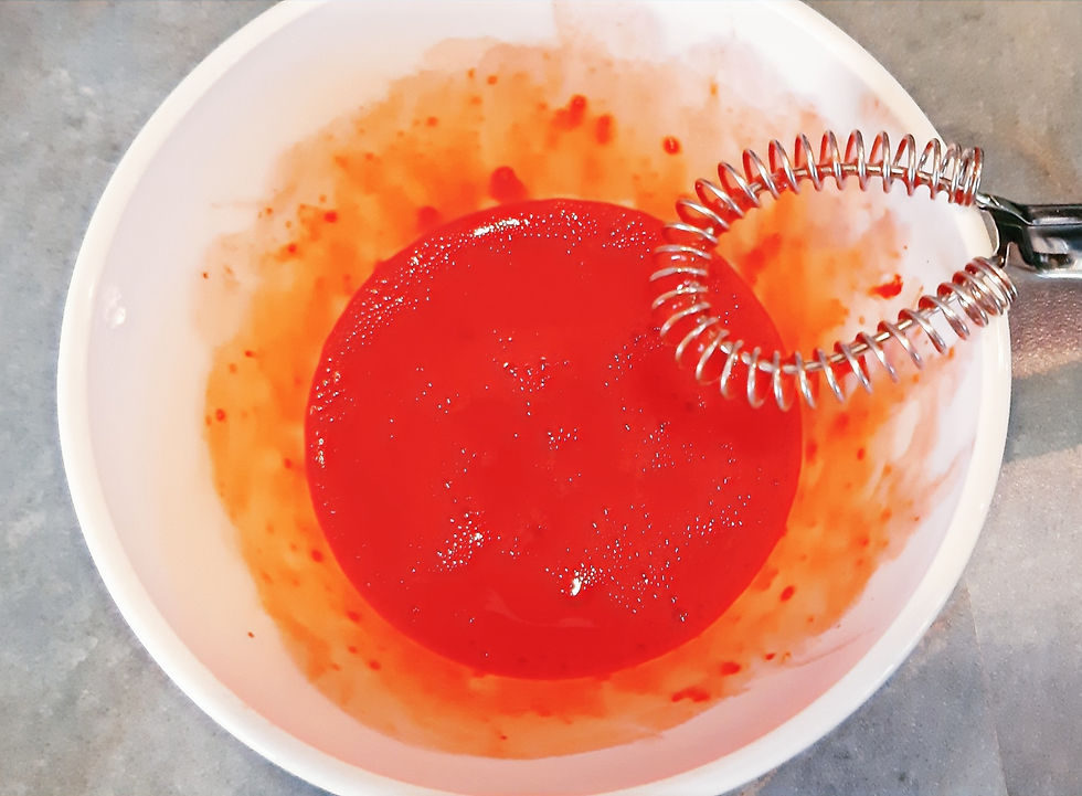 Œuf dans un bol mélangé au fouet avec colorant rouge