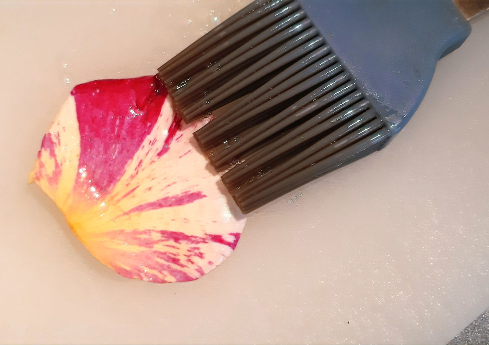 Pinceau en silicone badigeonnant de blanc d'œuf un pétale de rose.