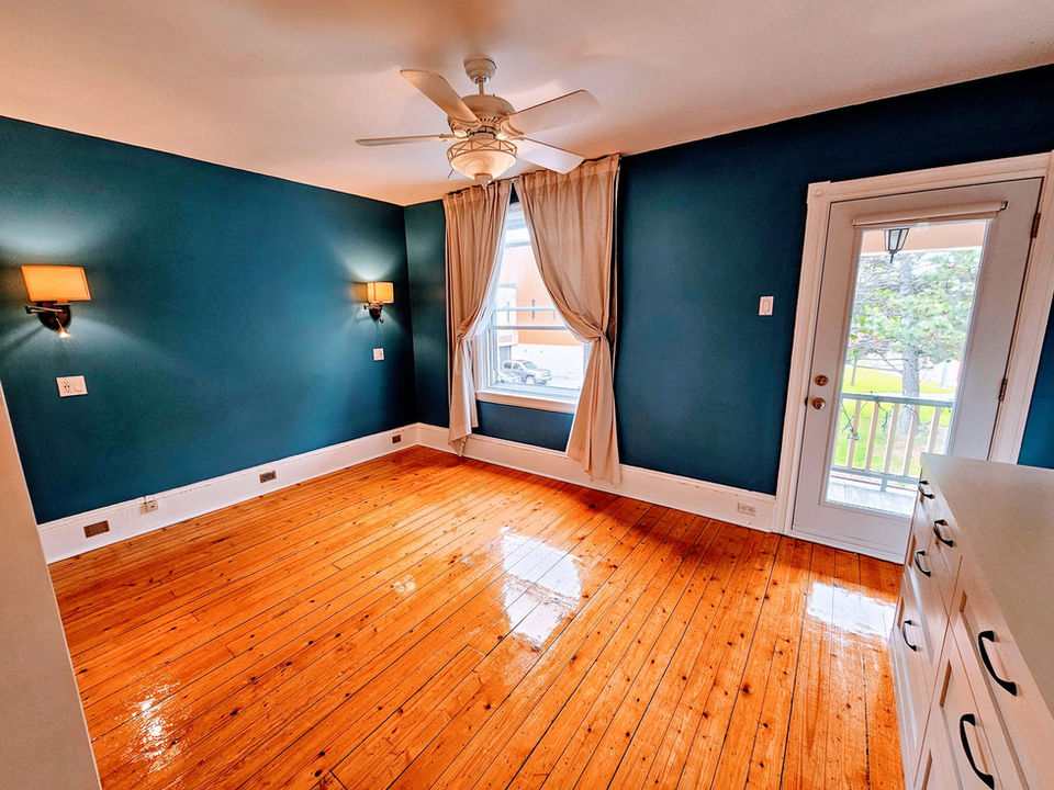 Spacious bedroom with hardwood floors and teal walls