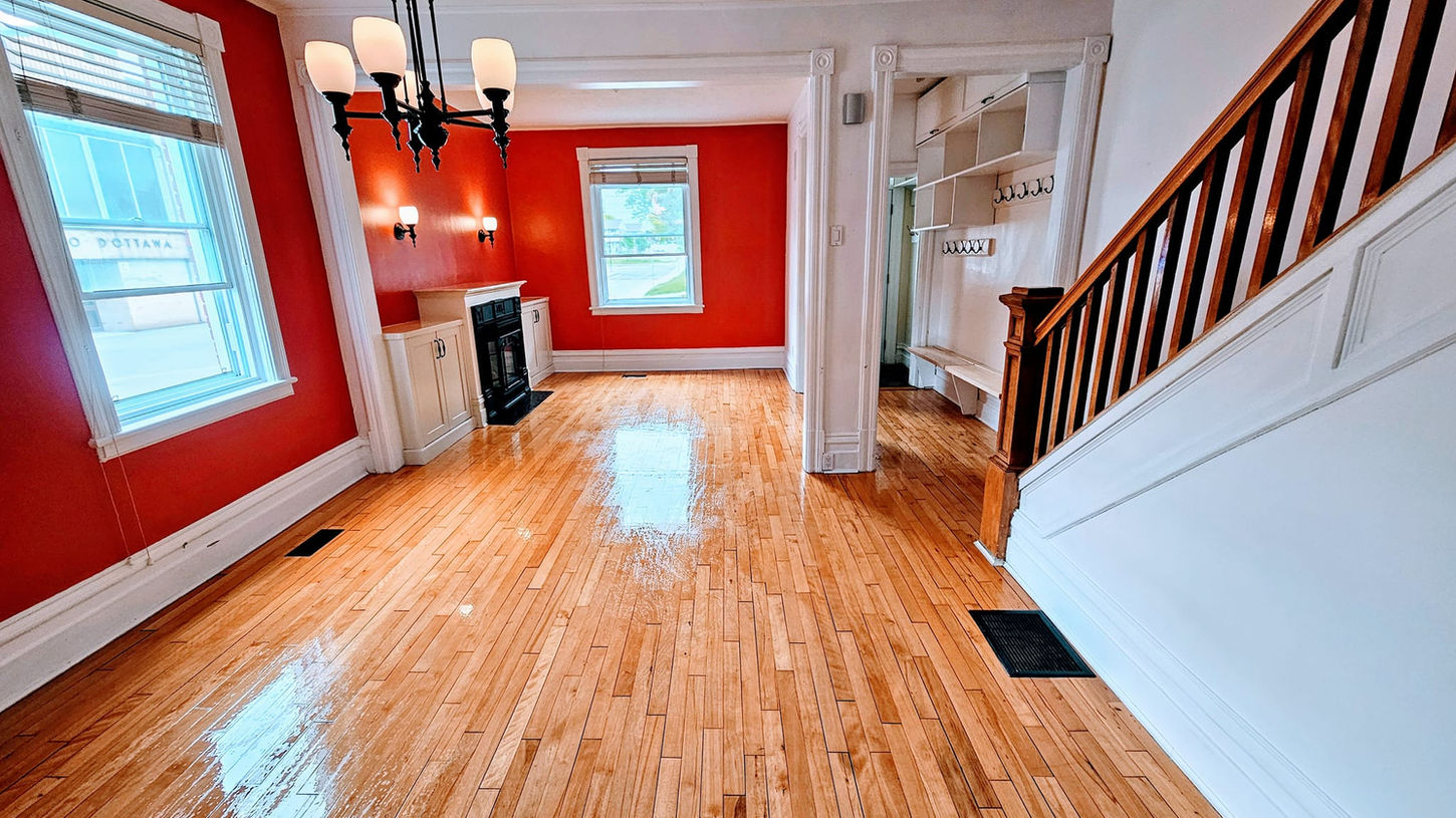Spacious red-walled living room with hardwood floors and staircase