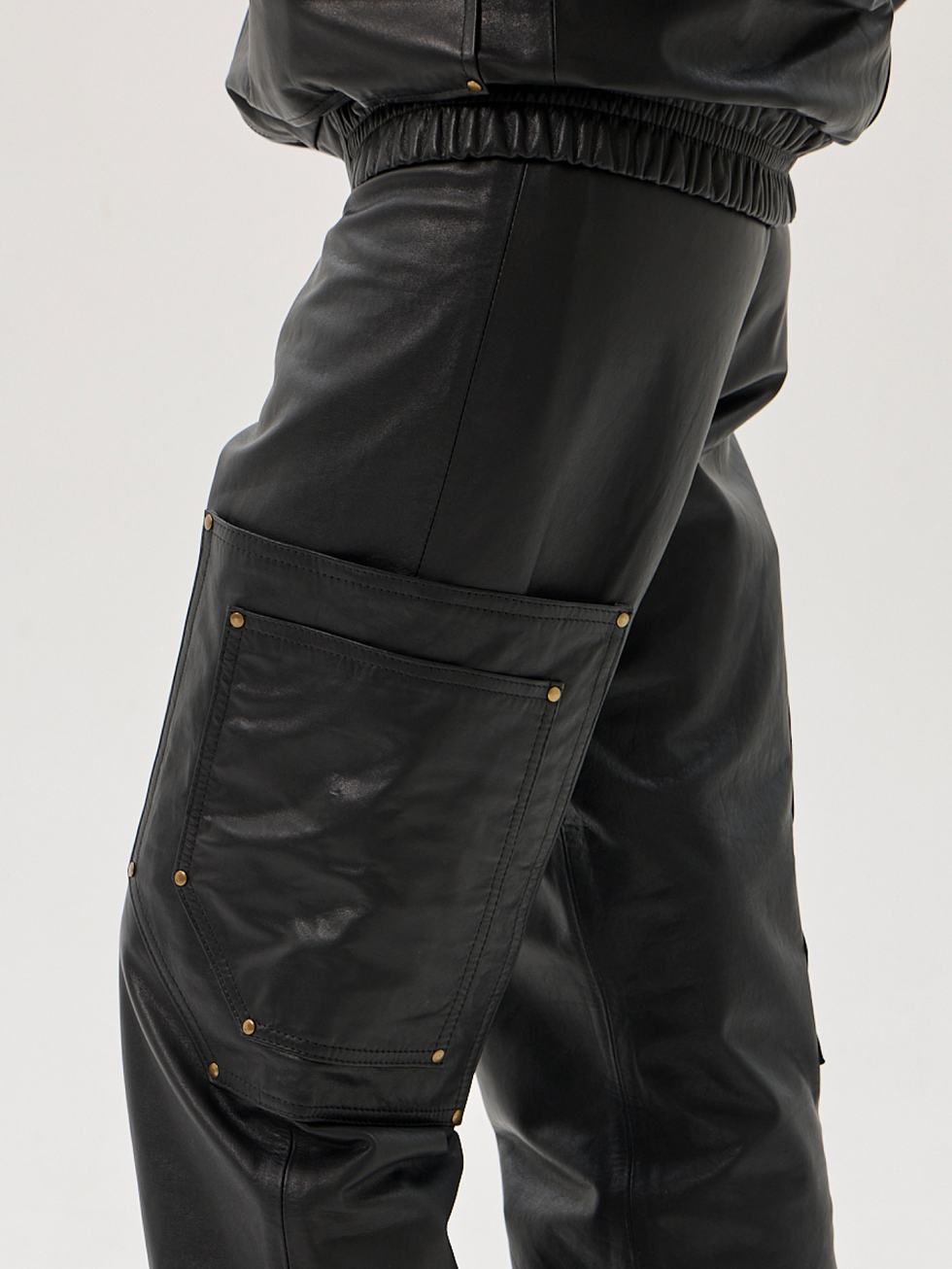 Black calfskin cargo pants with elastic waist and cuffs, oversized pockets and riveted detailing
